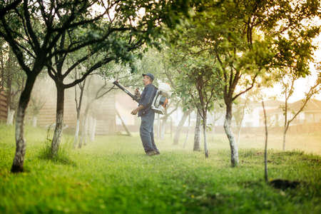 Industrial worker and farmer using spraying machine for pesticides and insecticide