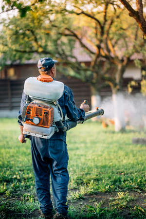 Agriculture farm worker spraying organic pesticides on fruit growing gardenの写真素材