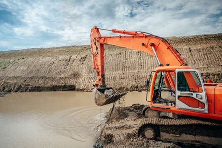 Industrial engineer working on excavator during highway construction site, loading dumper trucks and building viaduct and bridgeの写真素材