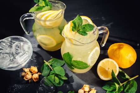 Preparation of a lemonade cocktail. Lemonade in the jug and lemons with mintの写真素材