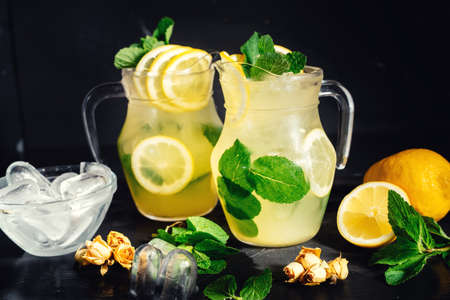 Lemonade with ice, lemon and lime slices in a jar in a black vintage summer backgroundの写真素材