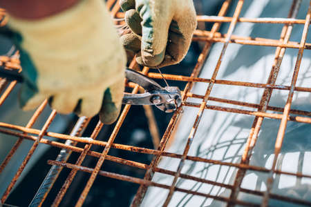 Details of steel reinforcement on construction site. Industrial construction worker using pliers and wire rodの写真素材