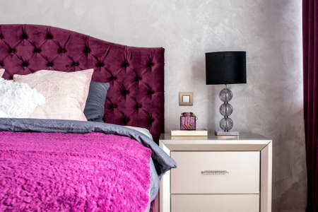 Matrimonial double bed in elegant and comfortable modern bedroom with nightstand lamp closeup. Interior design detailsの写真素材
