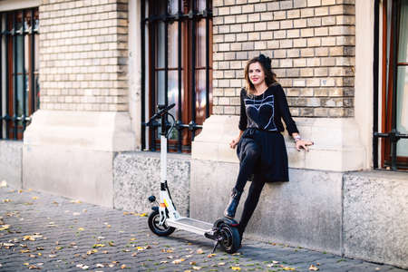 Close up portrait of smiling woman enjoying city traveling with electric scooterの写真素材