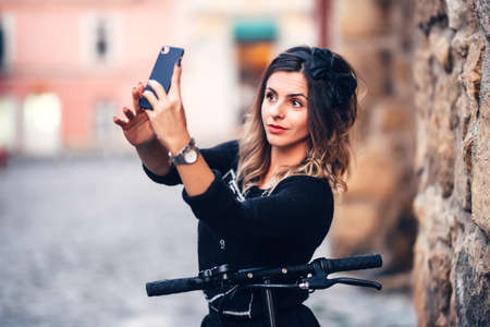 Beautiful young woman taking selfies on city streets