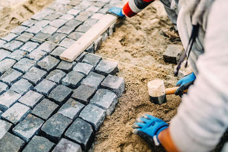 Industrial details of construction site - worker laying granite stones as walking pathの写真素材