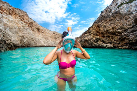 Portrait of attractive young woman posing with snorkeling mask, smiling and enjoying vacationの写真素材