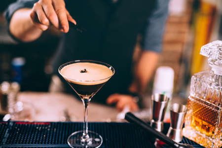 Iced coffee, whiskey based irish cocktail. Close up of bartender hand preparing beverage 