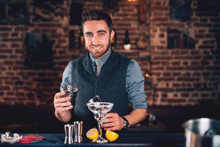 Smiling barman, professional waiter looking at camera and preparing cocktailの写真素材