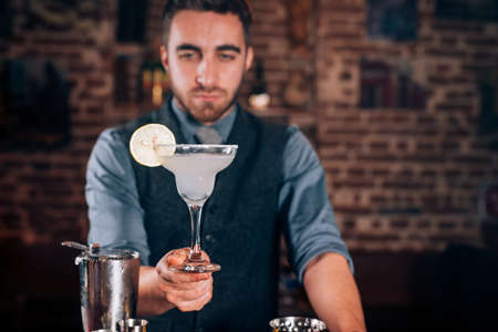 Handsome bartender, barman serving fresh made alcoholic beverage, margarita cocktailの写真素材