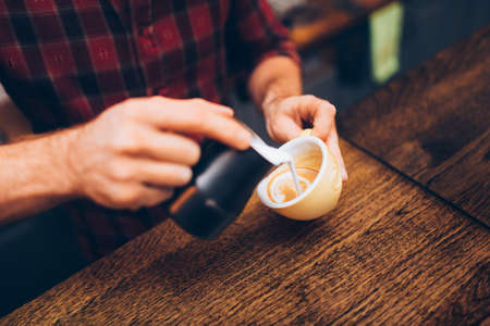 Professional barista pouring latte foam over coffee, espresso and creating a perfect delicious cappuccinoの写真素材