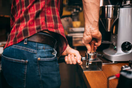professional bartender making coffee and preparing tamper with fresh roasted coffee in cafe bar, pub or restaurantの写真素材