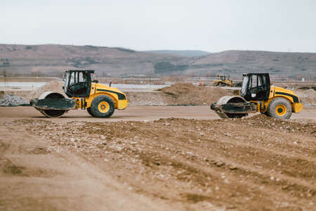 Two Vibratory Soil Compactors during road and highway construction. Industrial roadworks with heavy-duty machinery in construction siteの写真素材