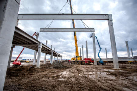 Construction site machinery, heavy duty crane working on assembly of concrete elementsの写真素材