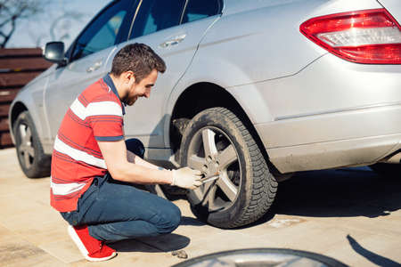 Automobile problems - man chaning tires, seasonal summer tiresの写真素材