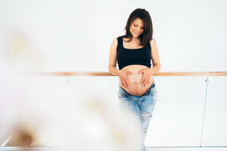 pregnancy, motherhood and future mother with expectation concept - happy pregnant woman with big belly in new living roomの写真素材