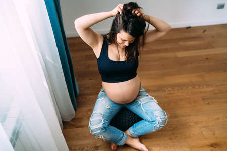 Pregnant woman at home smiling at baby bellyの写真素材
