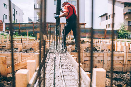 building construction worker pouring cement or concrete with pump tube. Details of worker and machineryの写真素材