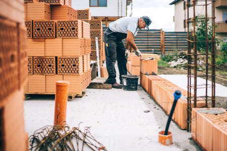 Close up details of industrial bricklayer installing bricks on industrial building, construction siteの写真素材