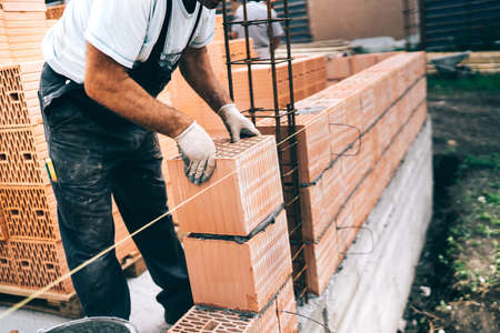industrial worker, bricklayer, mason working with bricks and building house