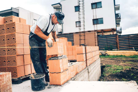 Industrial mason on construction site working with bricks and building walls. masonry details