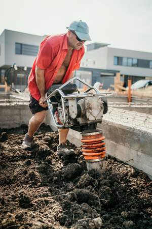 Industrial portrait of worker using vibratory tamper soil compactorの写真素材