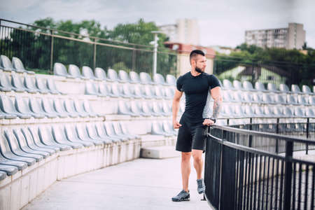 Athlete working out. Portrait of fitness man in park, stadium doing leg workoutの写真素材