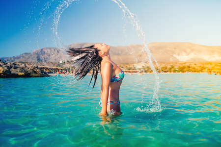 beautiful woman splashing water with her hair. Portrait of summer lifestyle and beach activitiesの写真素材