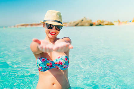 woman in swimsuit and straw hat smiling on tropical beach, enjoying sunny days and vacation