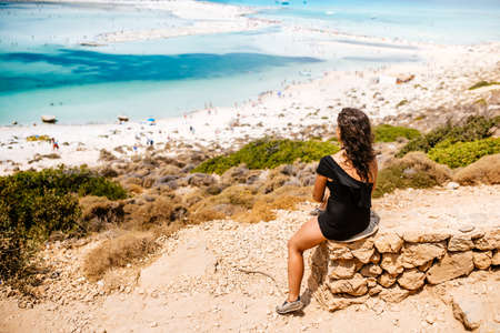 Beautiful woman wearing one piece swimming suit looking at sea from the cliffs. Woman enjoying summer and having a carefree holidayの写真素材