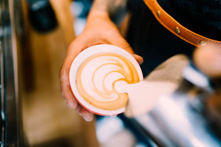 Professional barista pouring latte foam over coffee, espresso and creating a perfect cappuccinoの写真素材