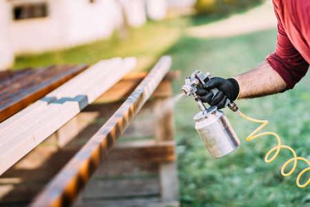 Industrial handyman, male construction worker painting with spray gun on siteの写真素材