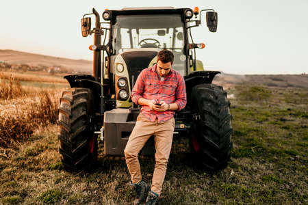 Modern agriculture with technology and machinery concept. Portrait of smiling farmer using...