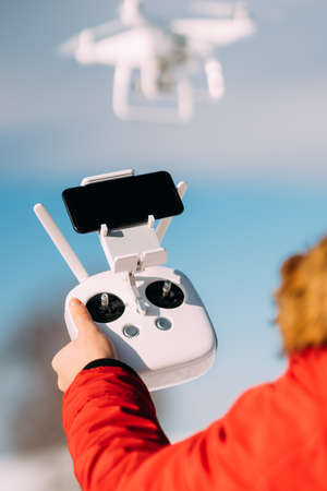 close up details of drone remote control and white drone in blue sky. Man operating drone, pilotage detailsの写真素材