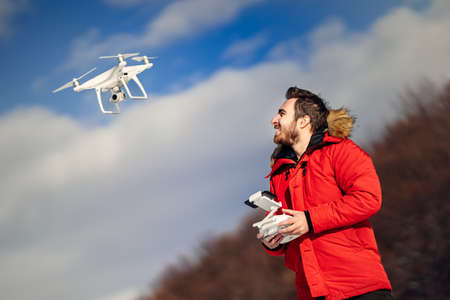 Aerial photography and drone footage details with man operating drone, flying over blue skyの写真素材