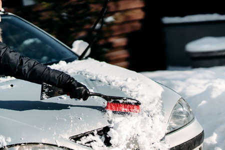 Details of man removing snow off the car during snowfall.  Winter details, car car maintenanceの写真素材