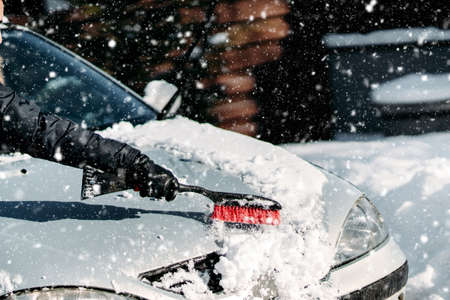 Details of man removing snow off the car during snowfall.  Winter details, car car maintenanceの写真素材
