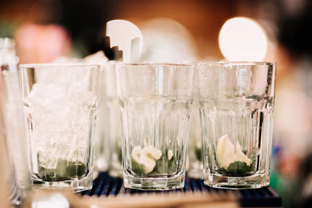 three glasses with ice, mint and lemon. Mojito preparation details. Barman and cocktails detailsの写真素材