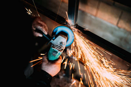 construction industry details - close up of metalworker using disc grinder for cutting metalの写真素材
