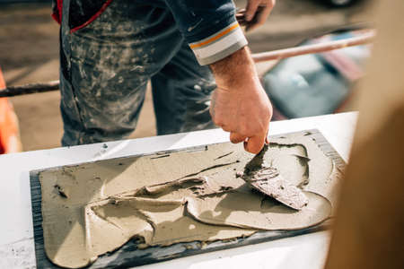 ceramic tiles. the worker's hand adding adhesive on marble, stoneの写真素材