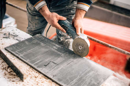 Construction site details - industrial tool, worker with angle grinder cutting marble and granite stoneの写真素材
