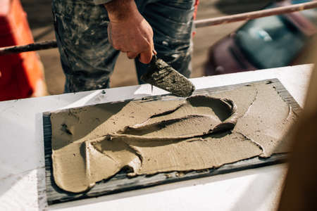 Details of industrial worker using mortar for stone installation on construction siteの写真素材