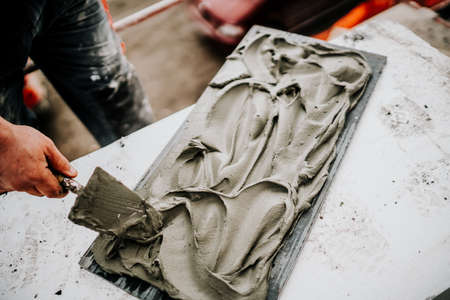 Industrial worker hands working on construction site and placing stone tiles on facade, architecture detailsの写真素材