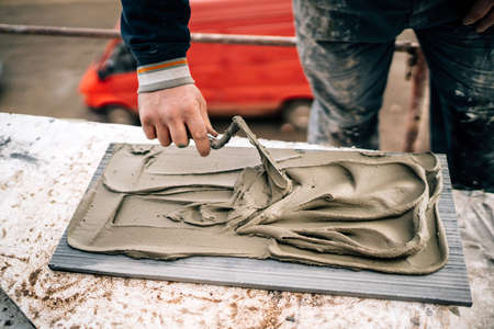 Close up of handyman fixing and applying ceramic tiles or marble stone on architecture facade