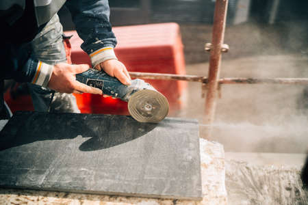 Close up details of worker cutting stone marble with angle grinder at construction siteの写真素材
