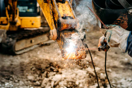 Mechanical engineer working and welding excavator on construction siteの写真素材