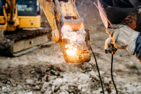 Close up details of mechanic, worker welding excavatorの写真素材