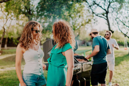 Girls wearing sunglasses, smiling and laughing at barbecue outdoor party, backyard summer concept