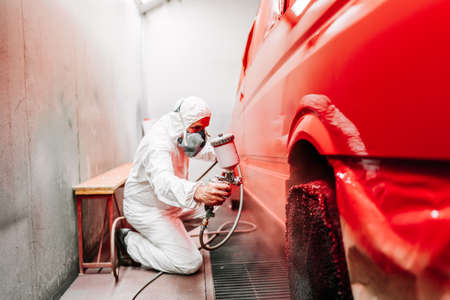 Mechanic working on painting a red car in special boothの写真素材