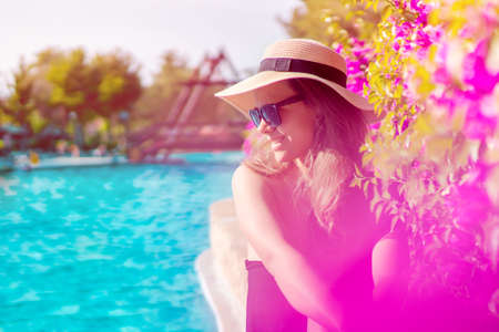 Portrait of beautiful woman wearing sunglasses by the pool, getting a tan by the swimming poolの写真素材
